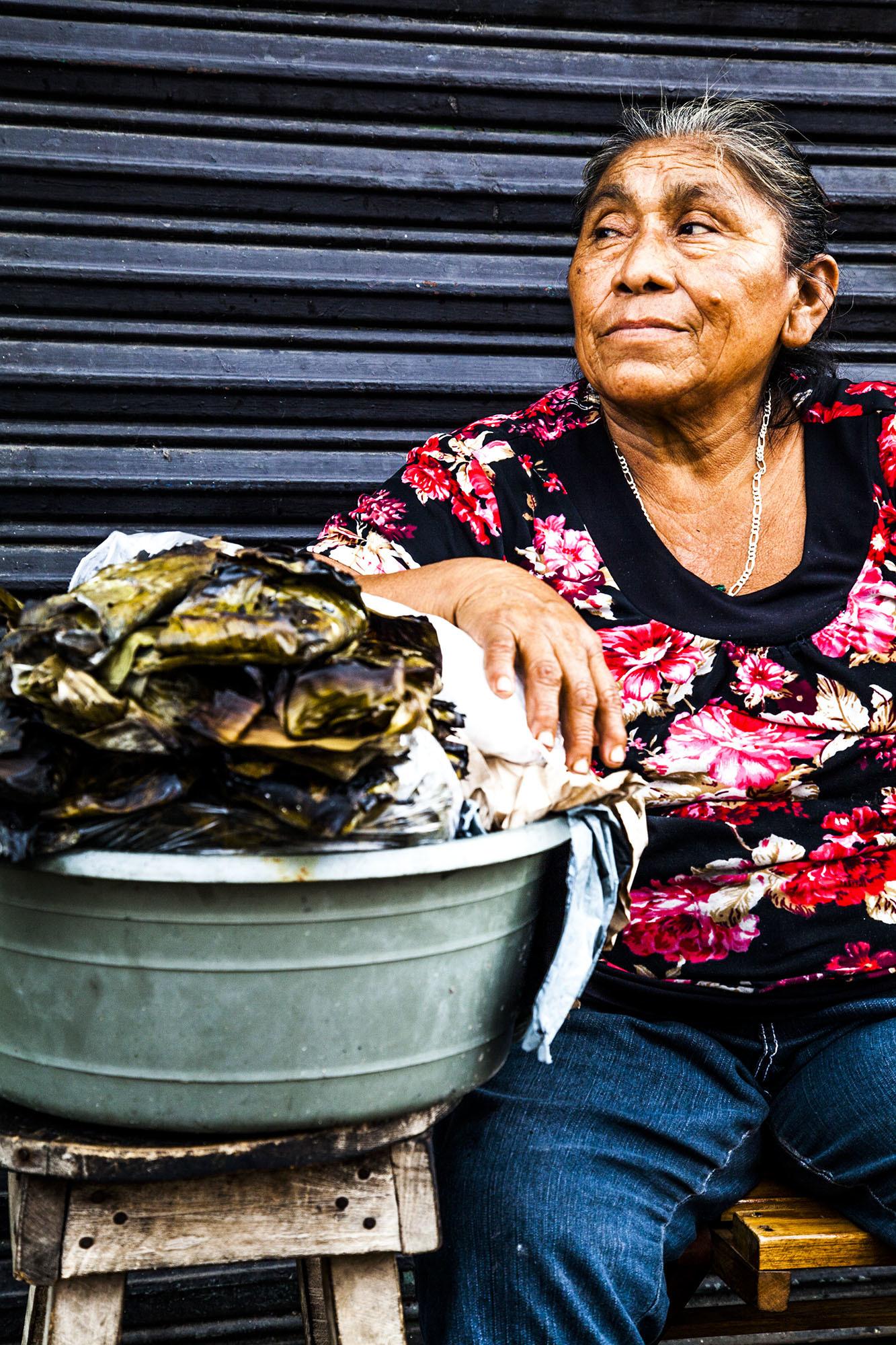 Mexican woman sitting by a container of street food in Valladolid Mexico