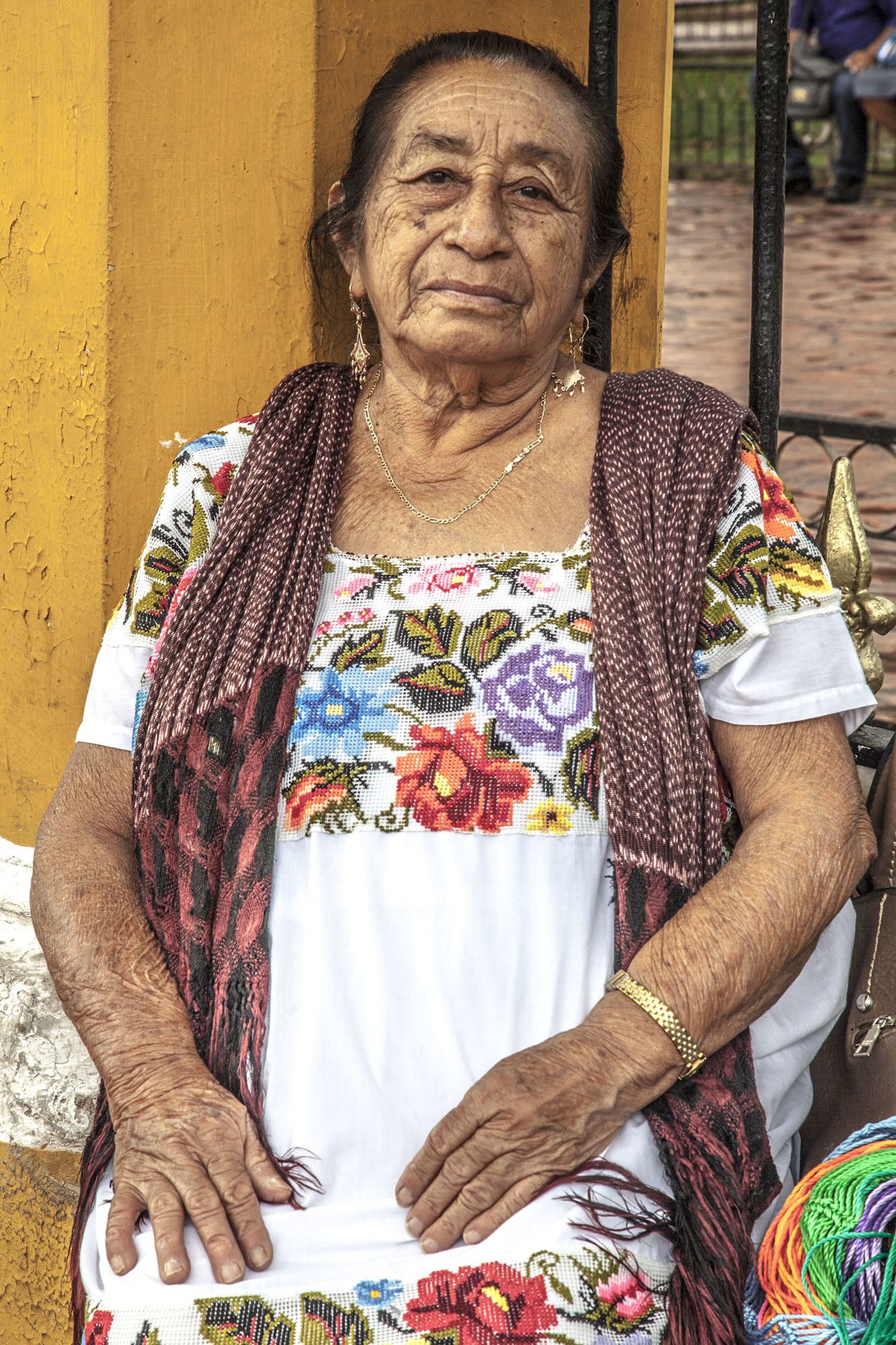 Mexican woman wearing traditional dress sitting by a park in Valladolid Mexico