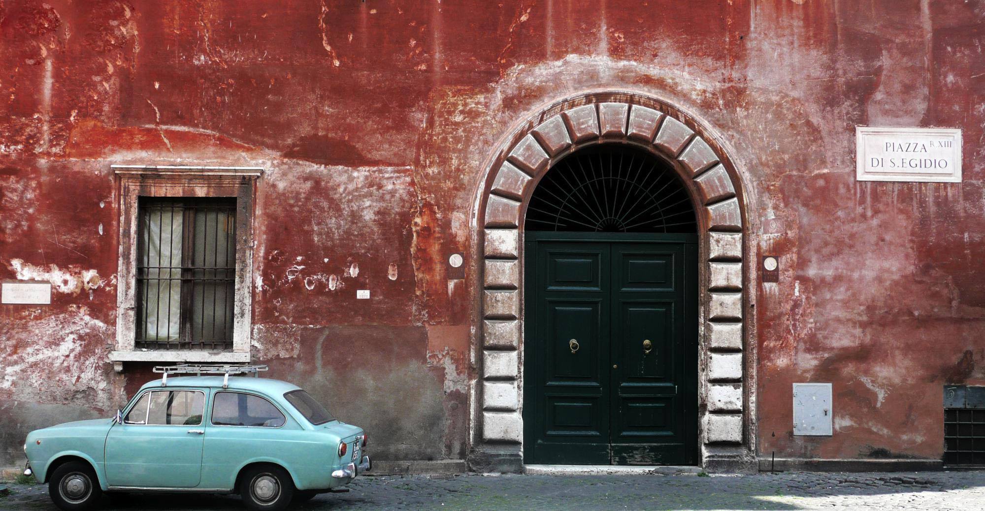 Old car against ancient wall in Trastevere Rome Italy