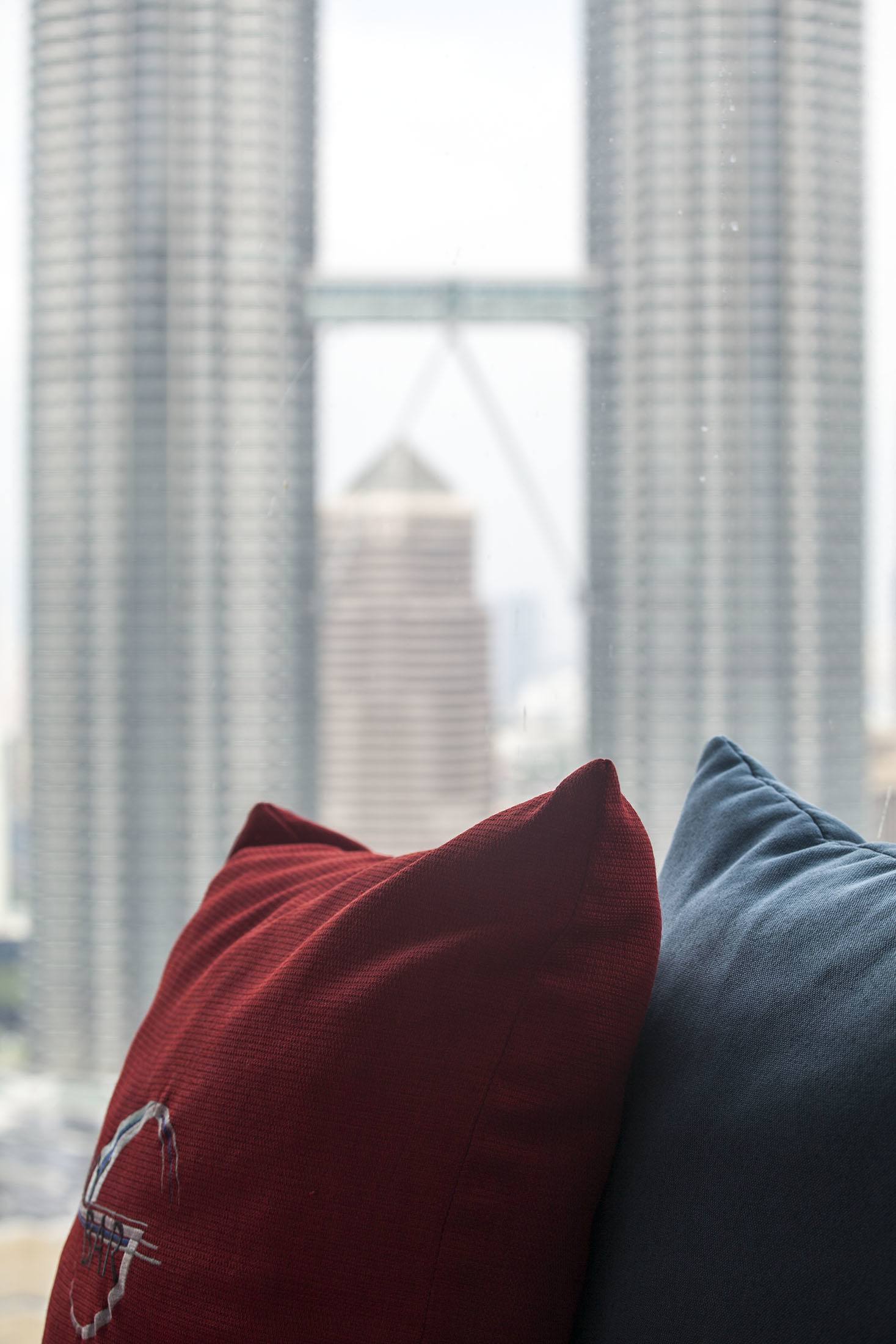 Pillows by a window of a hotel looking out at Petronas Towers in Kuala Lumpur Malaysia