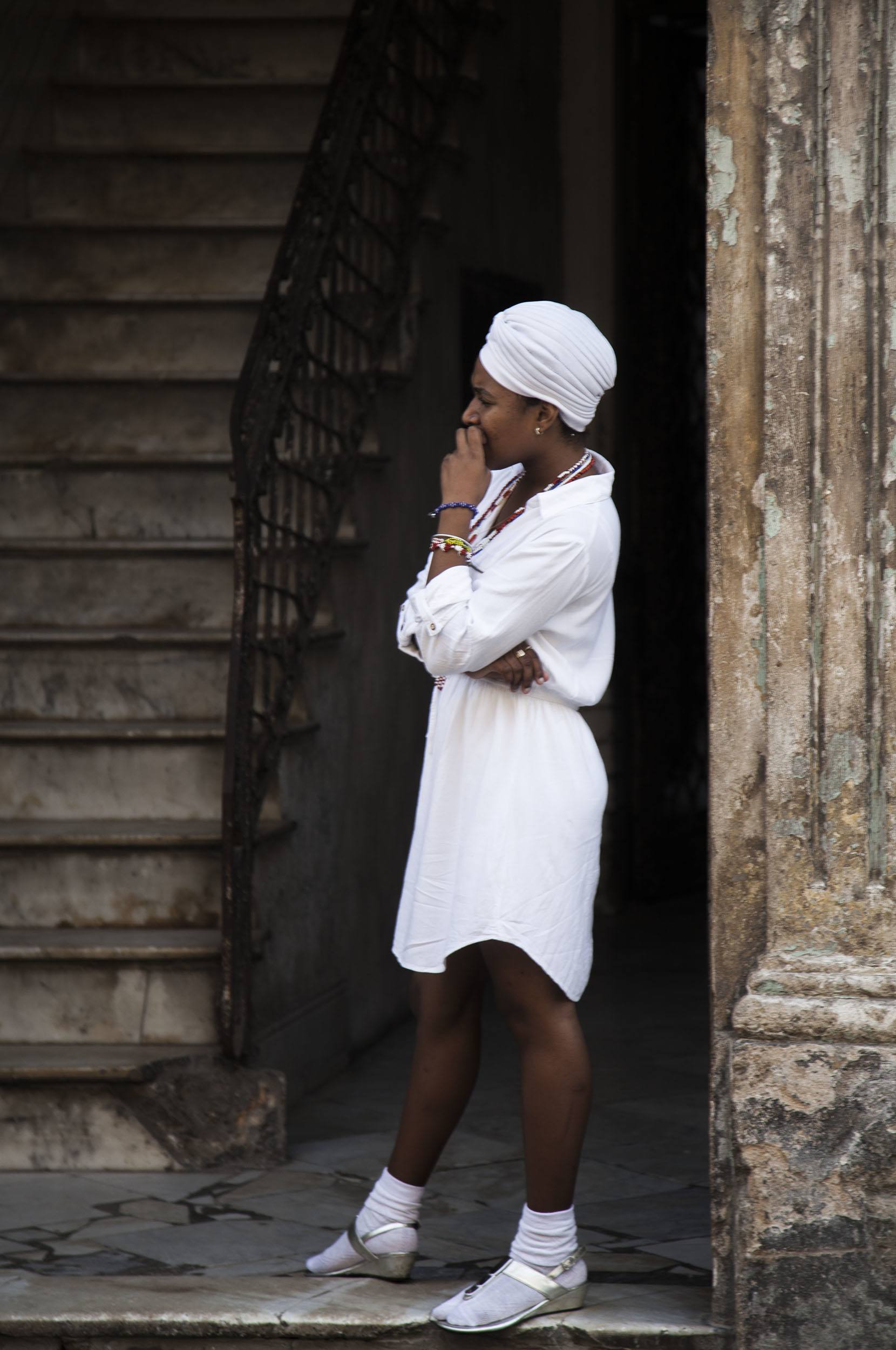 Woman dressed in white standing in the doorway of a house in Havana Cuba