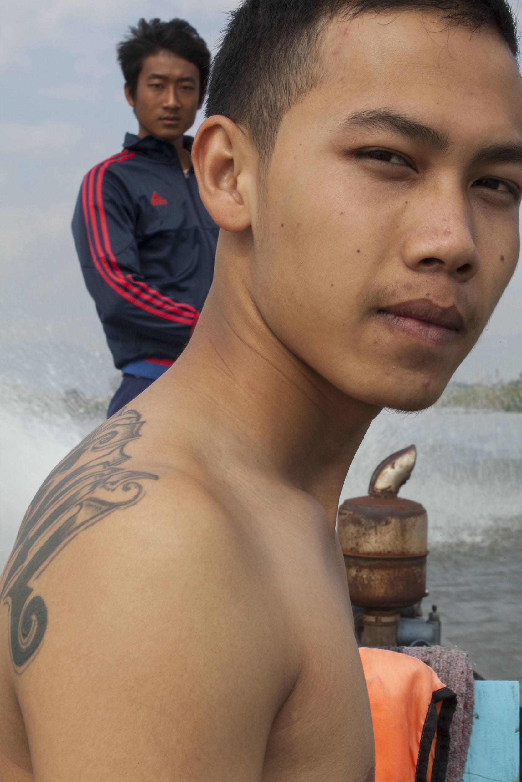 Young shirtless man on a boat crossing Inle Lake in Myanmar