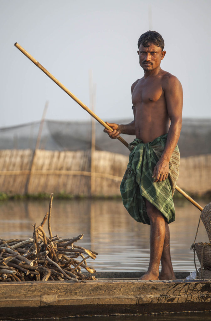 Shirtless man on boat of waterways near Sreemangal, Bangladesh