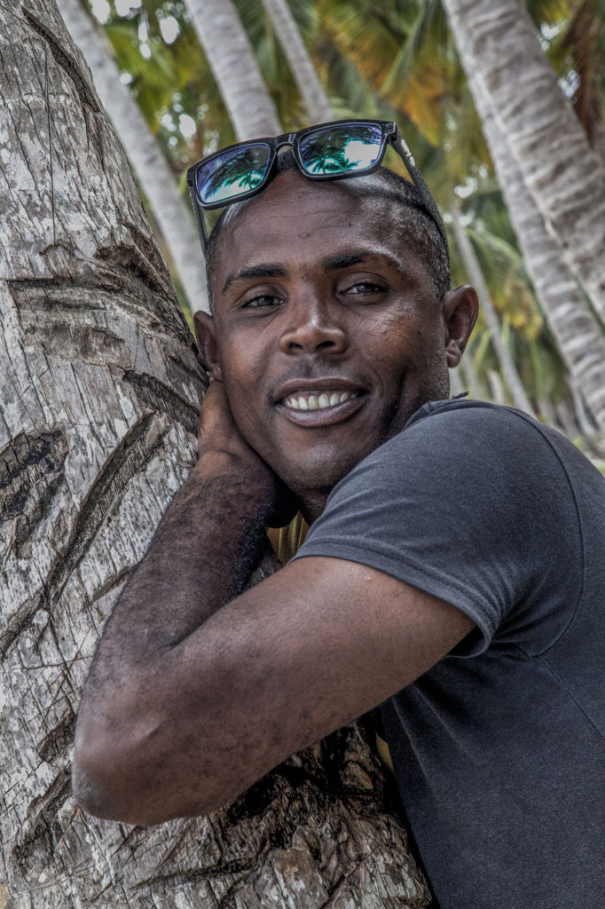 Dominican man leaning against a coconut tree on Playa Madama Dominican Republic